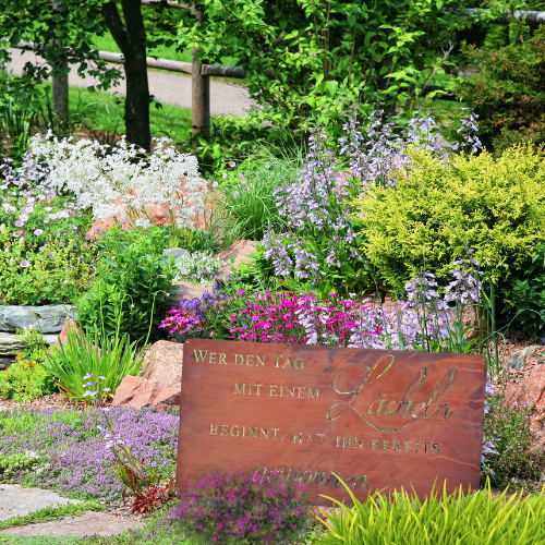 Edelrost Home Deko Schild auf Bodenplatte als Gartendeko vor grünem Hintergrund